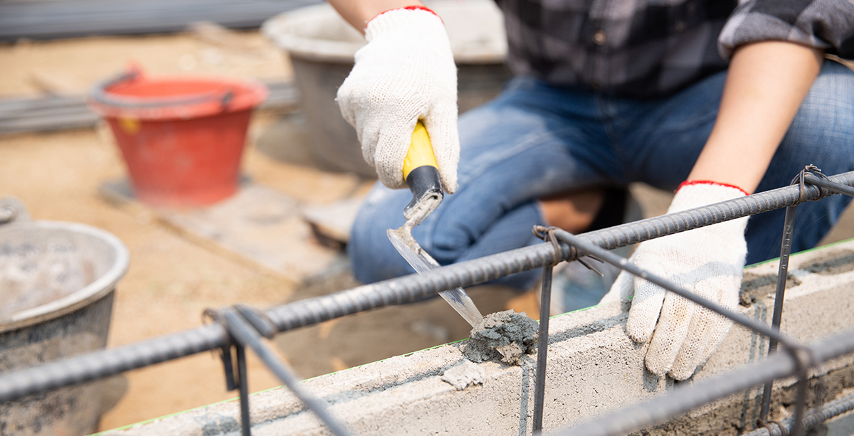 Bricklayer worker installing brick masonry on exterior wall with trowel putty knife